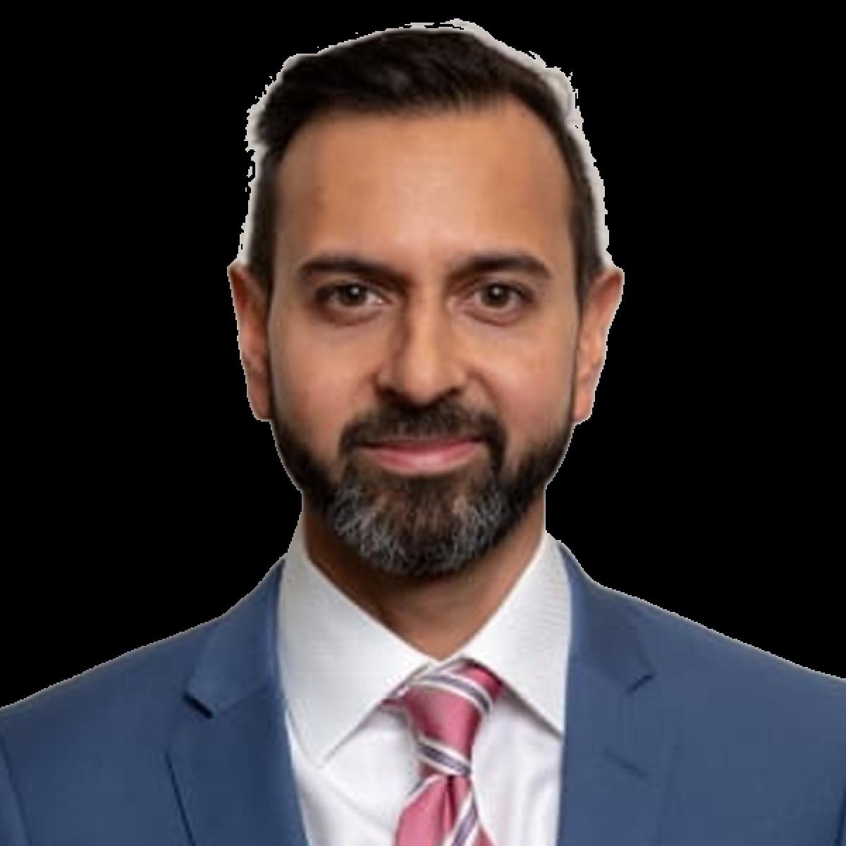 Professional male doctor in blue suit and pink tie, smiling at camera